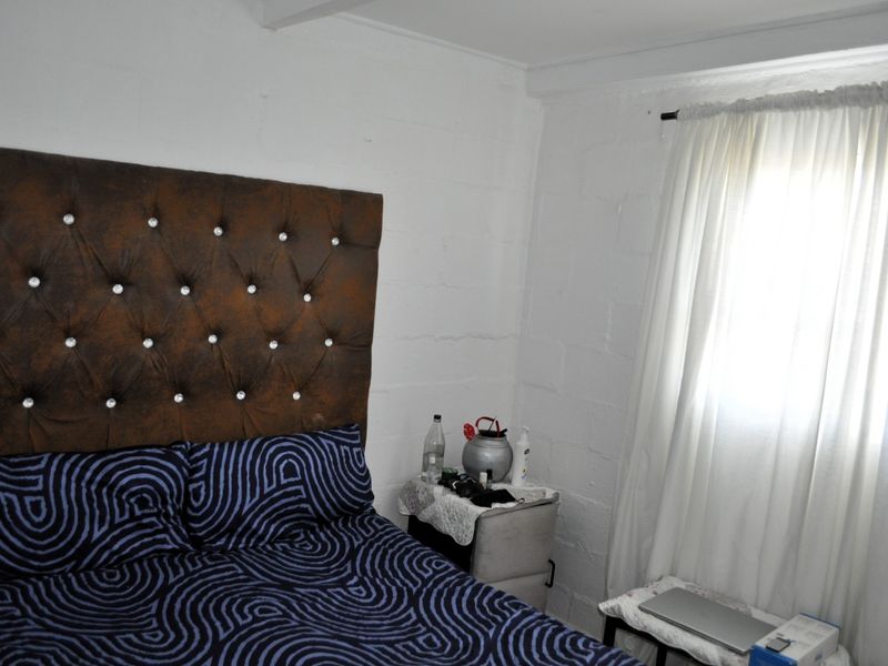 A bedroom featuring exposed blockwork walls and a window with a curtain rail.