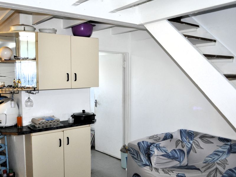 A compact kitchen area featuring built-in cabinetry and a staircase, offering potential for modernization and improved layout efficiency.