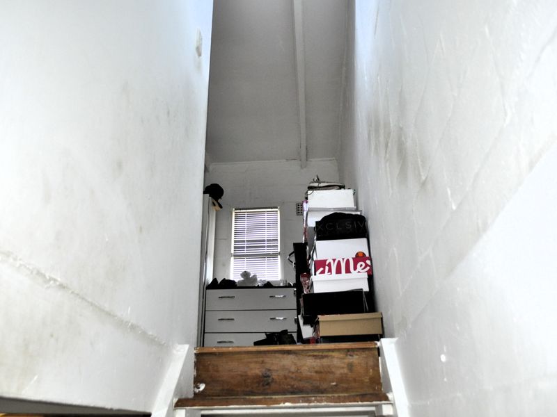 A narrow staircase leading to an upper landing area with visible wall staining and worn wooden stair treads.