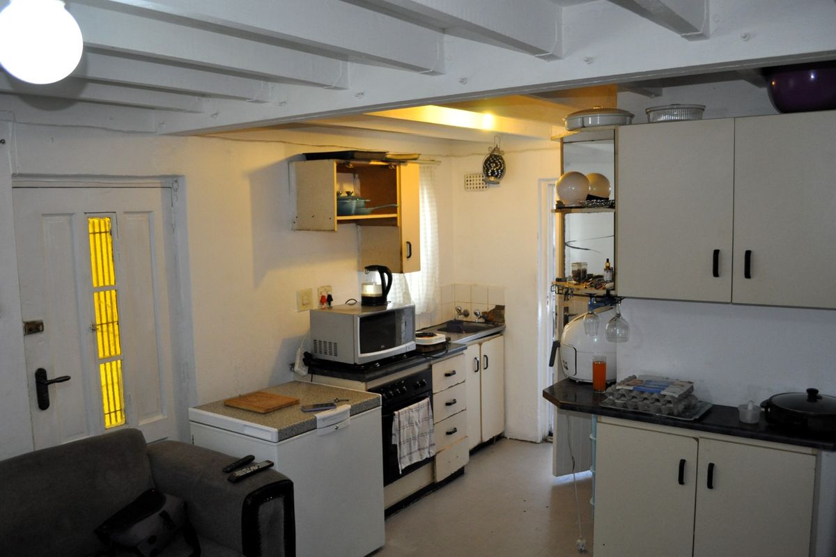 A compact kitchen area featuring built-in cabinetry, exposed ceiling beams, and a functional layout with integrated cooking appliances.