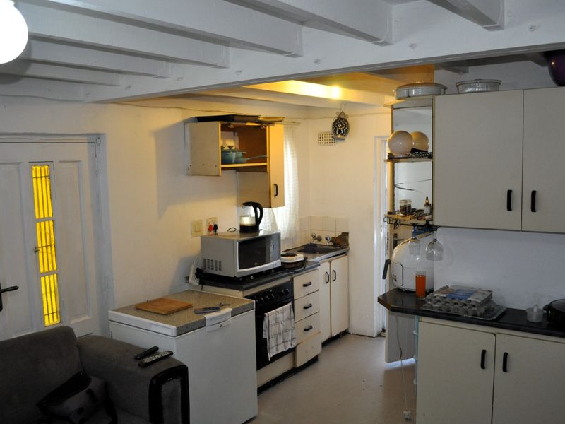 A compact kitchen area featuring built-in cabinetry, exposed ceiling beams, and a functional layout with integrated cooking appliances.