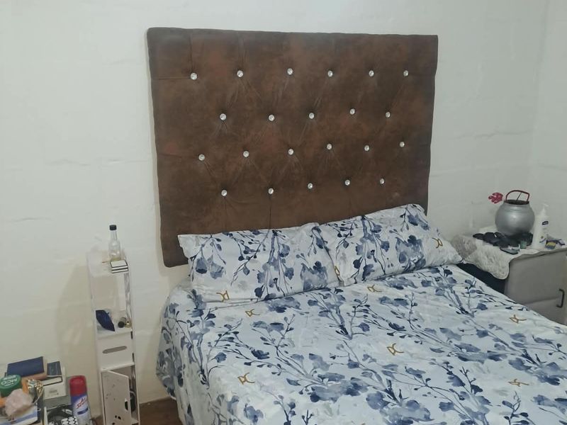 A bedroom featuring exposed blockwork walls and a ventilation grille, requiring cosmetic updates to improve the overall finish and aesthetic appeal.