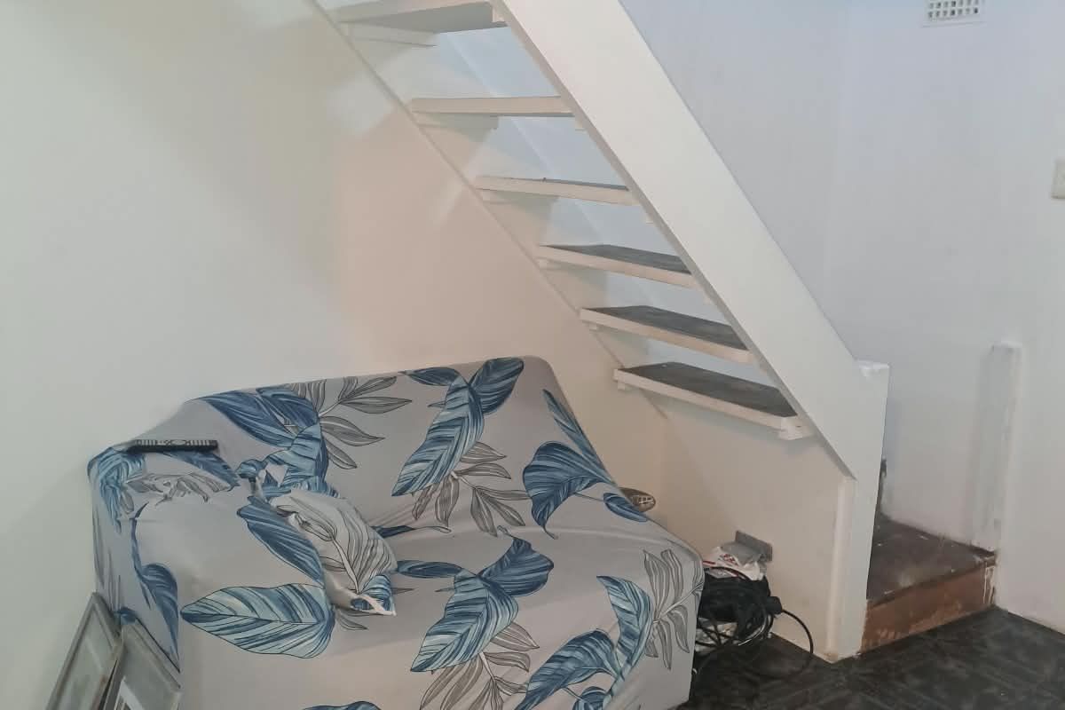 Living area featuring an open staircase with visible structural finishes and tiled flooring.