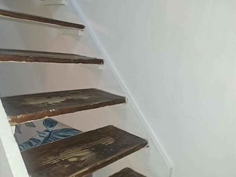 A staircase featuring worn wooden treads and painted stringers, showing signs of significant wear and requiring refinishing.