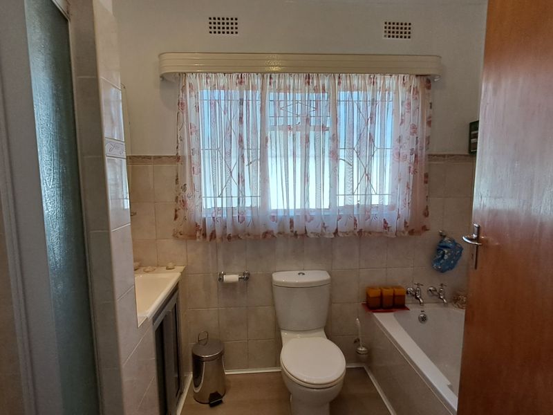 A functional bathroom featuring a bathtub, separate shower enclosure, toilet, and built-in vanity with tiled wall finishes.