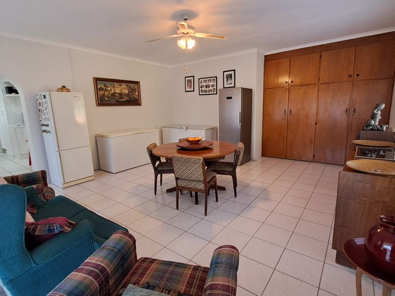 Spacious open-plan living and dining area featuring tiled flooring, a ceiling fan, and extensive built-in wooden storage cabinetry.