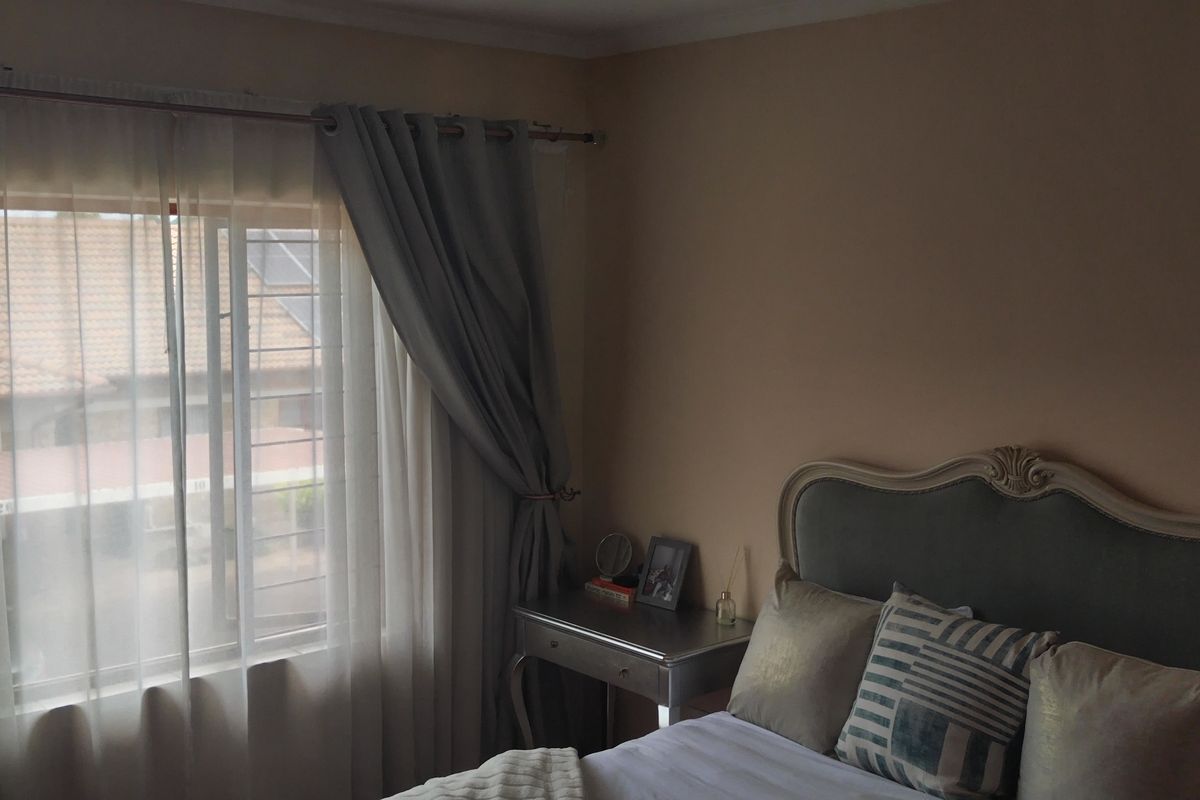 A bedroom featuring a window with security bars and curtain fixtures, providing natural light to the space.