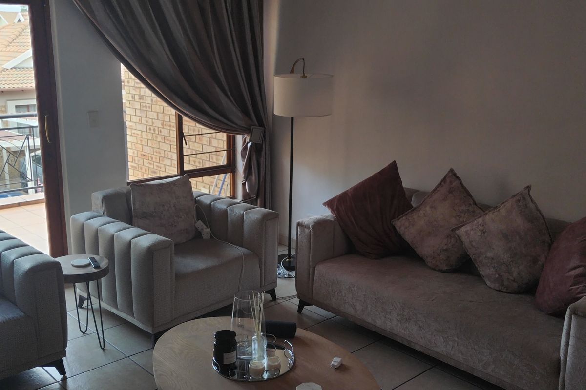 A comfortable living room featuring tiled flooring and a large sliding glass door that provides direct access to an outdoor balcony area.