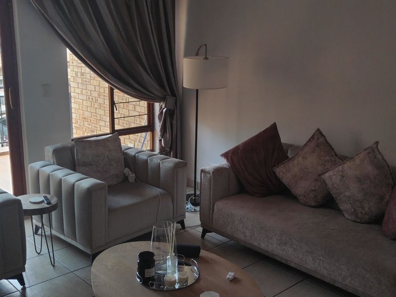 A comfortable living room featuring tiled flooring and a large sliding glass door that provides direct access to an outdoor balcony area.