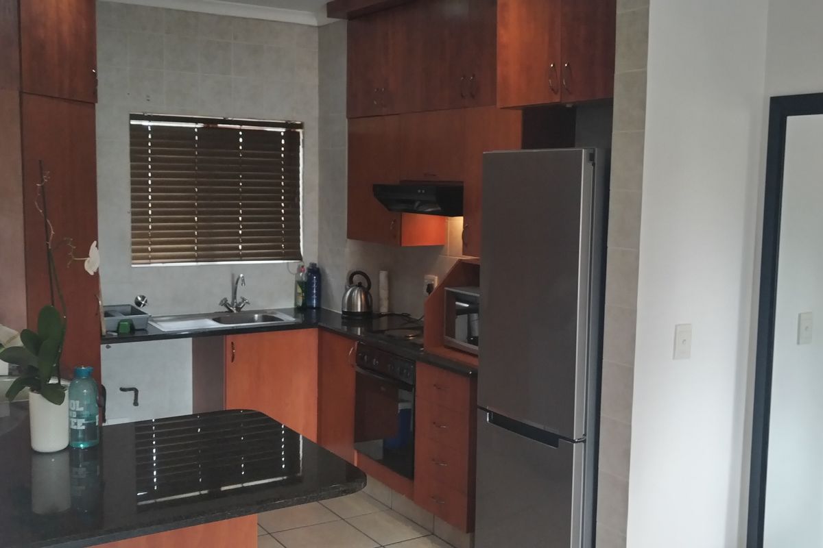 A functional kitchen featuring dark wood cabinetry, granite countertops, tiled flooring, and integrated appliances, offering a practical layout for daily use.