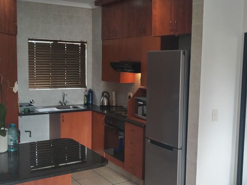 A functional kitchen featuring dark wood cabinetry, granite countertops, tiled flooring, and integrated appliances, offering a practical layout for daily use.