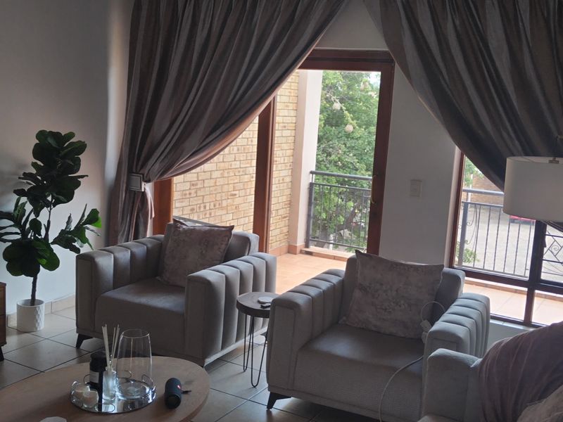 A comfortable living room featuring tiled flooring and large sliding glass doors that provide natural light and direct access to an outdoor balcony.