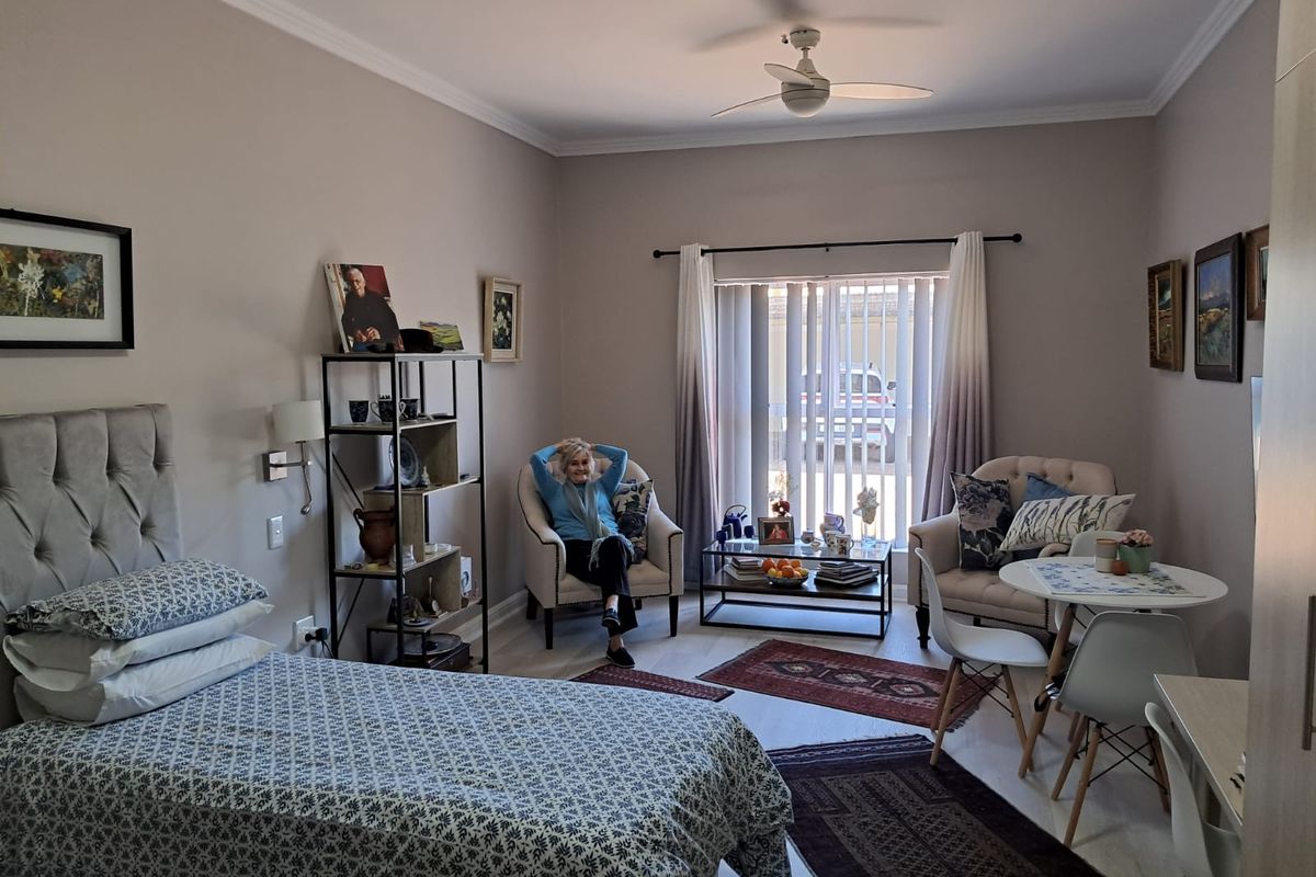 A well-maintained bedroom featuring a ceiling fan, neutral wall tones, and vertical blinds, offering a comfortable and functional living space.