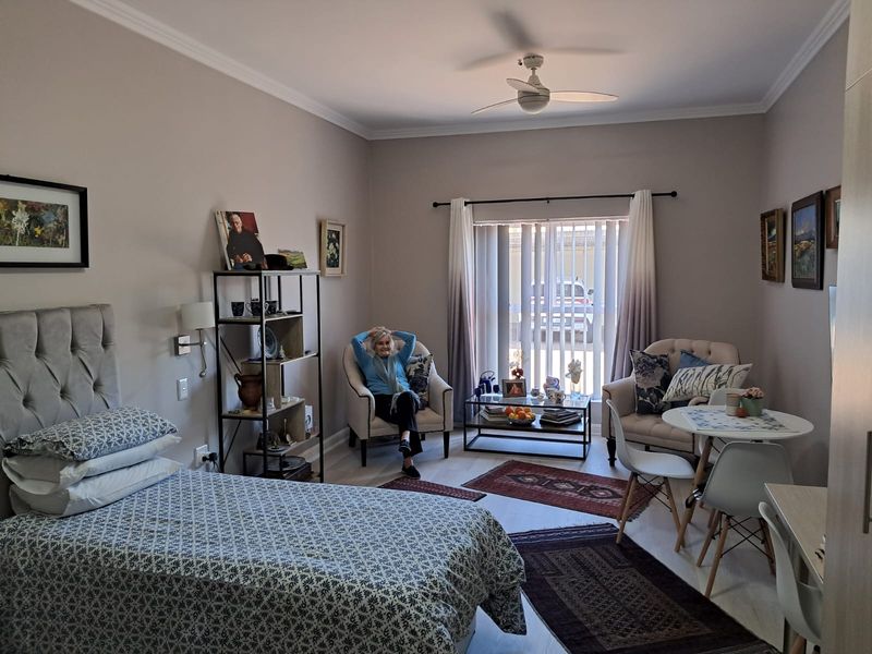 A well-maintained bedroom featuring a ceiling fan, neutral wall tones, and vertical blinds, offering a comfortable and functional living space.