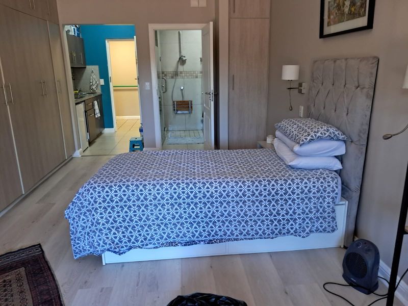 A well-maintained bedroom featuring light laminate flooring, extensive built-in cabinetry, and direct access to an en-suite bathroom.