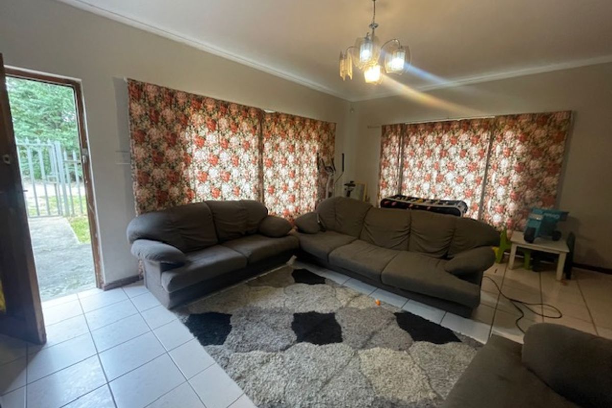 Spacious living room featuring tiled flooring, neutral wall tones, and direct access to the exterior through a side door.