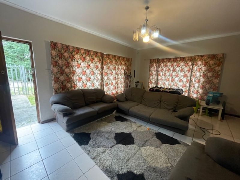 Spacious living room featuring tiled flooring, neutral wall tones, and direct access to the exterior through a side door.