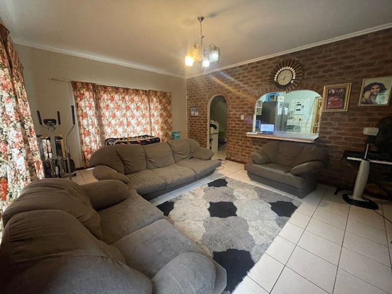 Spacious living room featuring an exposed brick feature wall, an arched entryway, and a convenient pass-through window connecting to the kitchen area.