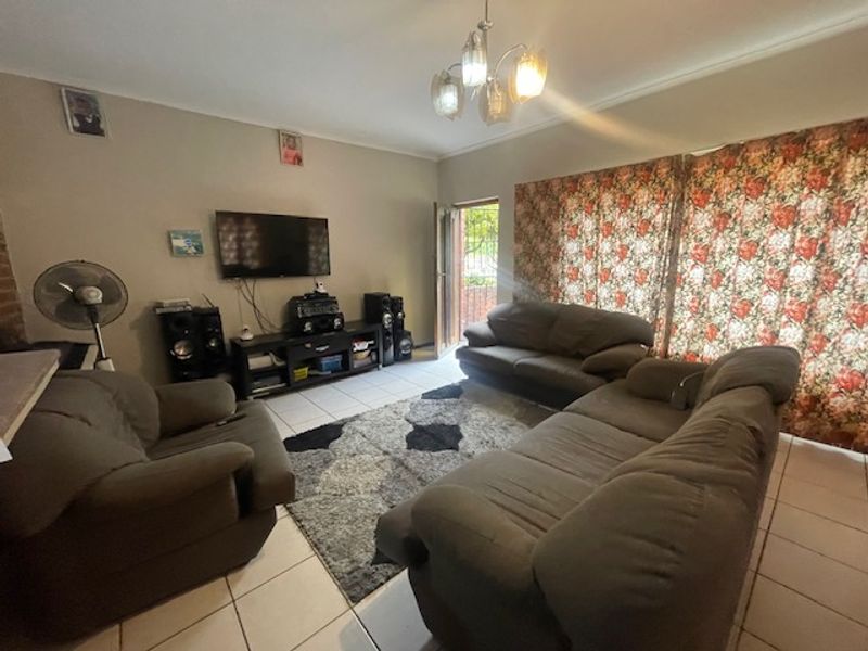 A functional living room featuring tiled flooring, a central light fixture, and access to an outdoor area via a sliding door.