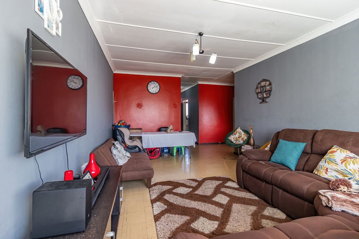 A living room area featuring tiled flooring and a multi-tone wall finish, providing a functional space for relaxation and dining.