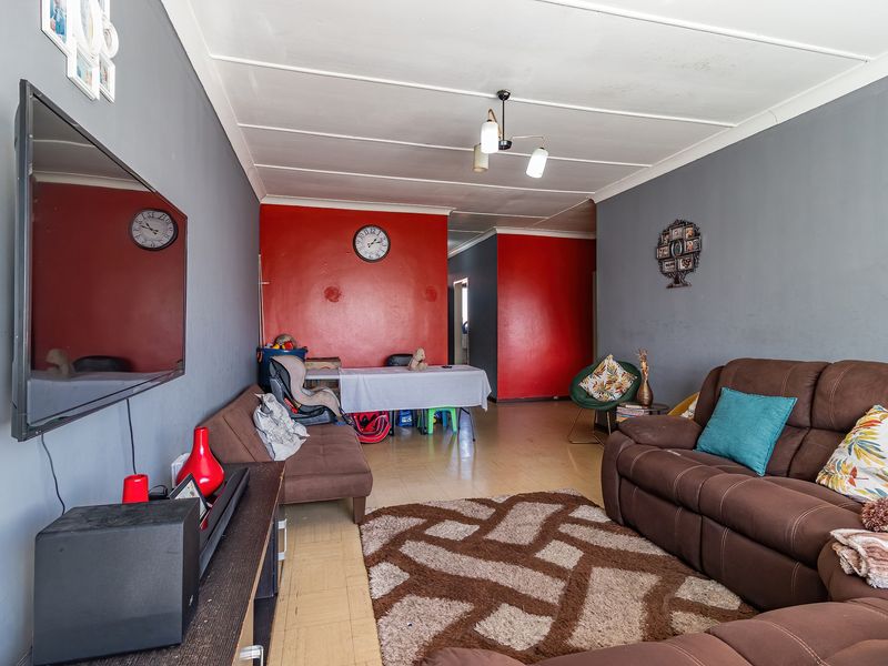 A living room area featuring tiled flooring and a multi-tone wall finish, providing a functional space for relaxation and dining.