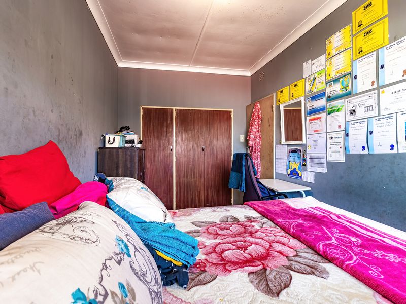 A bedroom featuring built-in wooden cupboards and coved ceiling detailing, currently requiring cosmetic updates to the wall and ceiling finishes.