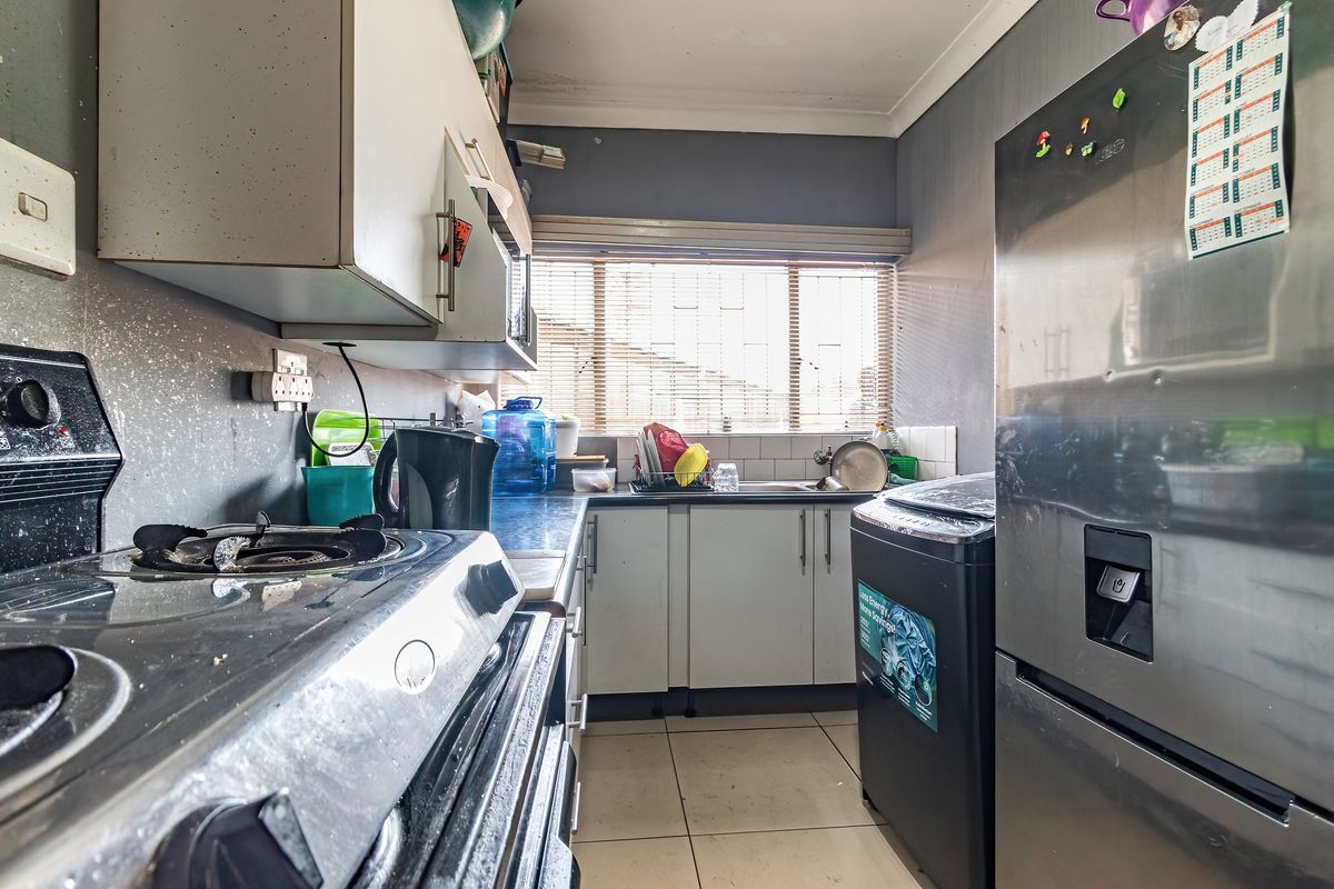 Compact kitchen featuring built-in cabinetry, a gas stove, tiled backsplash, and tiled flooring, offering a functional layout in need of cosmetic updates.