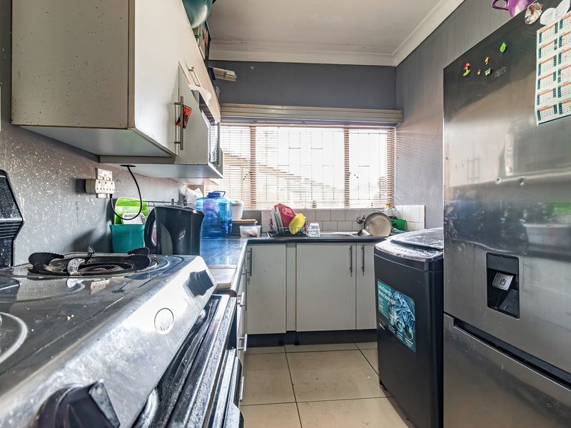Compact kitchen featuring built-in cabinetry, a gas stove, tiled backsplash, and tiled flooring, offering a functional layout in need of cosmetic updates.