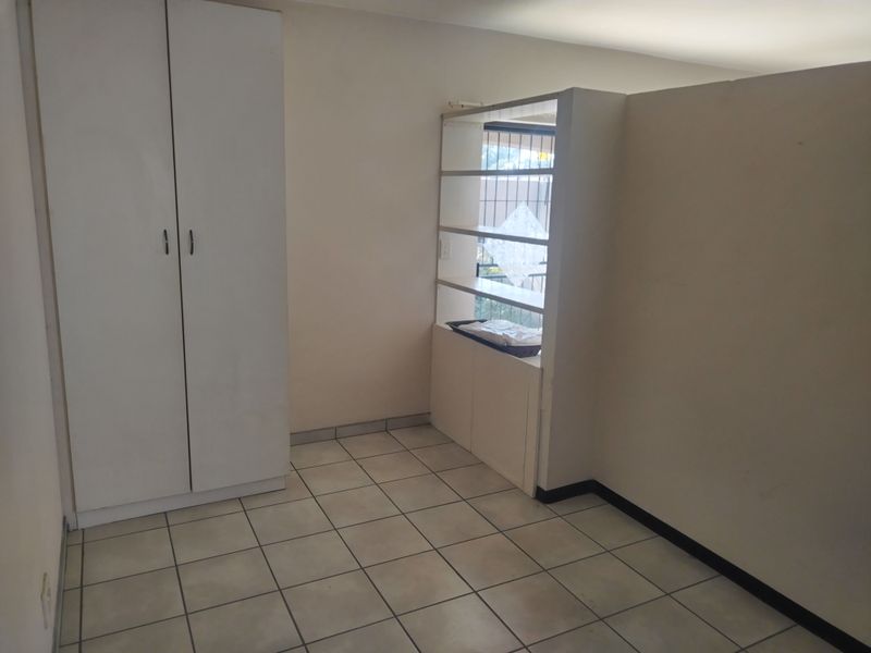 A vacant bedroom featuring tiled flooring, a built-in wardrobe, and a built-in shelving unit partition.