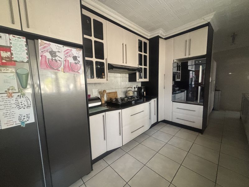 A functional kitchen featuring two-tone cabinetry, a gas hob with extractor fan, built-in oven, and tiled flooring.