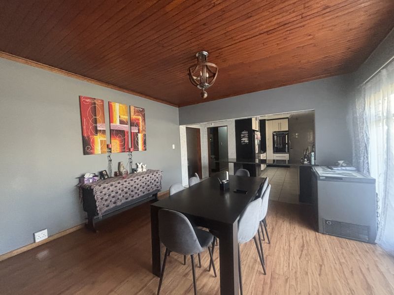 Open plan dining area featuring timber ceiling and laminate flooring, with a direct view into the adjacent kitchen space.