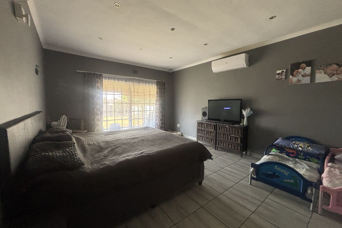 Spacious bedroom featuring tiled flooring, recessed downlighting, and a wall-mounted split-system air conditioner with direct access to the exterior.