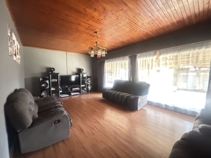 Spacious living room featuring warm timber tongue and groove ceilings, laminate flooring, and large sliding glass doors providing ample natural light.