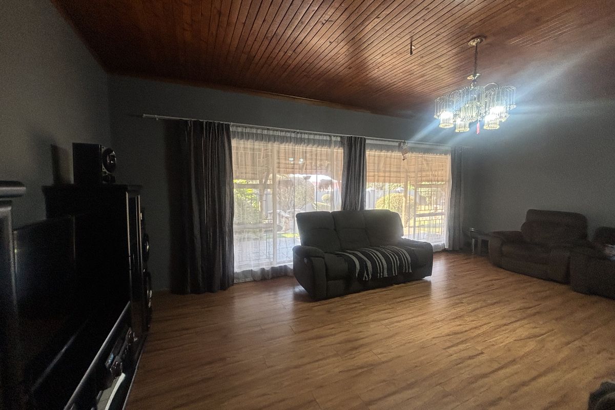 Spacious living room featuring a warm timber-clad ceiling, laminate flooring, and large sliding glass doors that provide ample natural light and garden access.