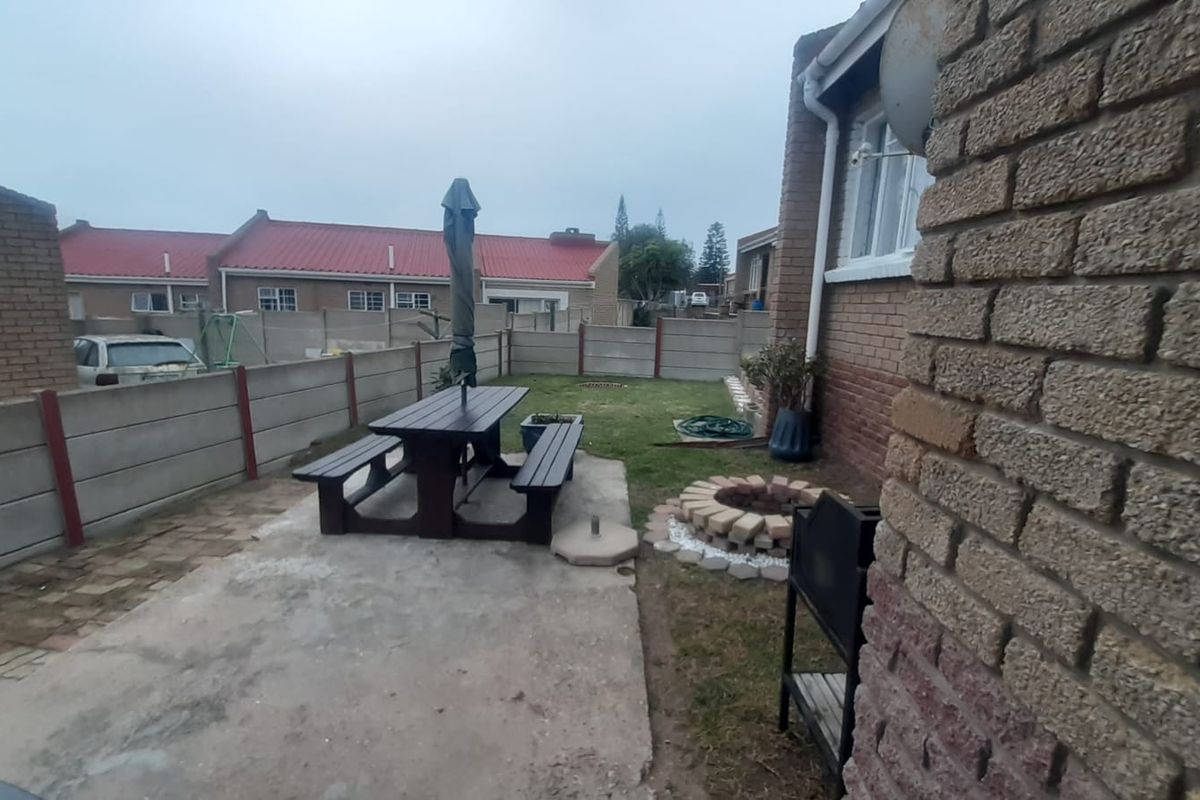 Rear garden area featuring a concrete patio, brick fire pit, and enclosed by precast concrete boundary walls.