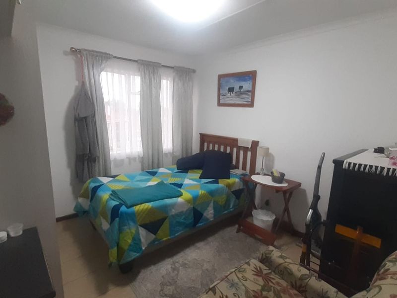 A standard bedroom featuring tiled flooring and window curtain rails, providing a functional space for rest.