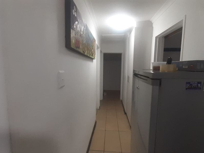 A functional hallway featuring tiled flooring and overhead lighting, providing access to various rooms within the home.