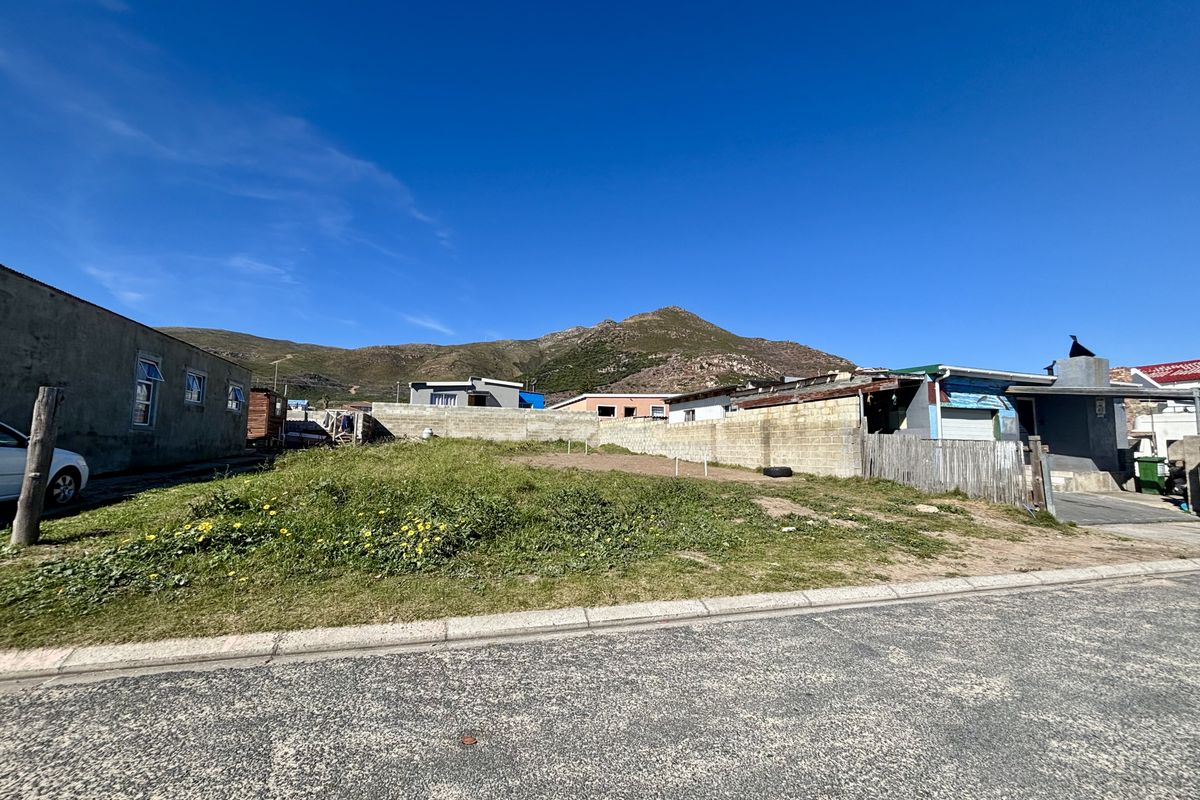 A vacant residential plot featuring a boundary wall and street access, situated in a neighborhood with mountain views.