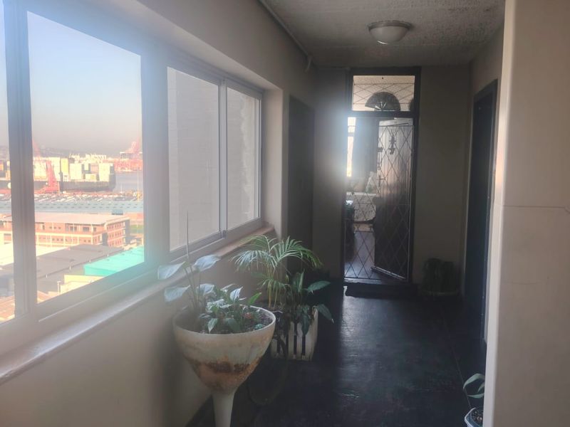 Enclosed balcony area featuring large windows with harbor views, a security gate, and direct access to the interior living space.