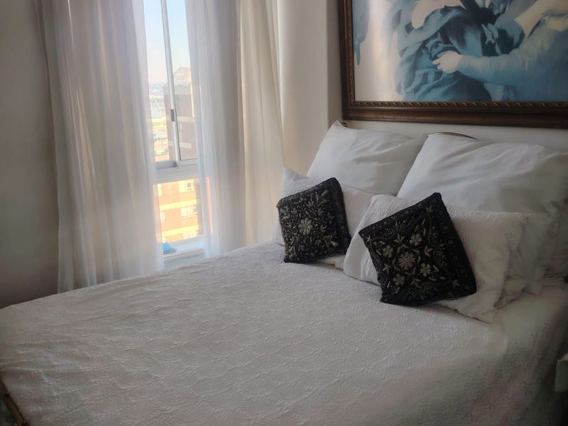A cozy bedroom featuring a large window with natural light and neutral wall finishes, providing a comfortable and bright living space.