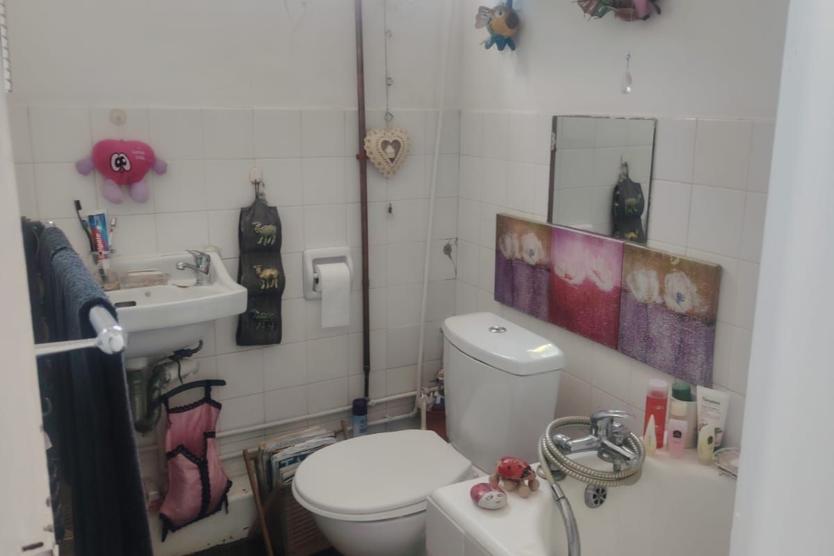 Compact bathroom featuring a wall-mounted basin, toilet, and bathtub with tiled splashbacks and an overhead electric water heater.