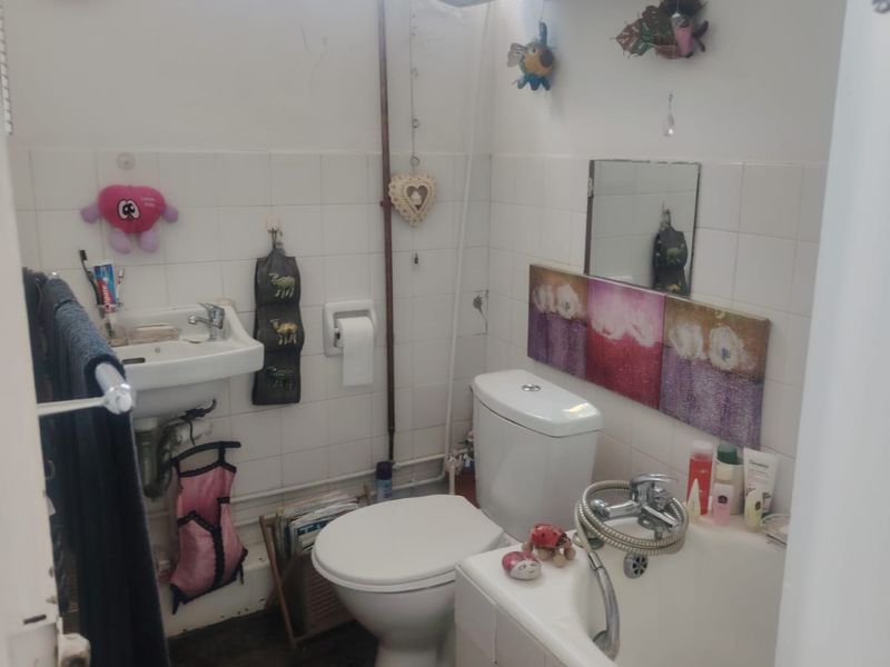 Compact bathroom featuring a wall-mounted basin, toilet, and bathtub with tiled splashbacks and an overhead electric water heater.