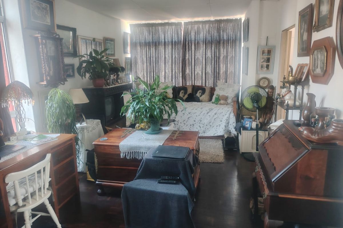 A living room space featuring dark hardwood flooring and large windows with curtains, offering a functional area for relaxation.