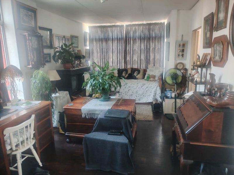 A living room space featuring dark hardwood flooring and large windows with curtains, offering a functional area for relaxation.