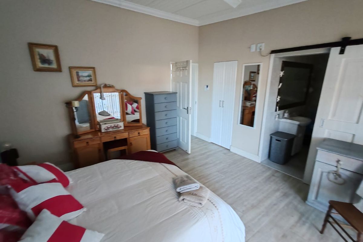 A bedroom featuring light laminate flooring, a ceiling fan, built-in wardrobe, and a sliding barn door leading to an en-suite bathroom.