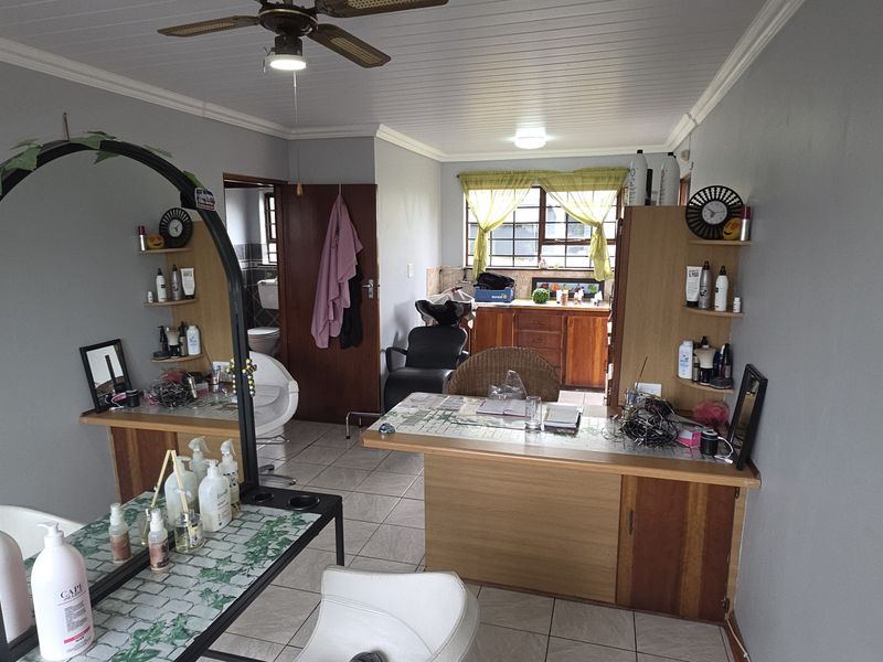 A multi-purpose room currently utilized as a salon, featuring tiled floors, built-in cabinetry, and a ceiling fan.