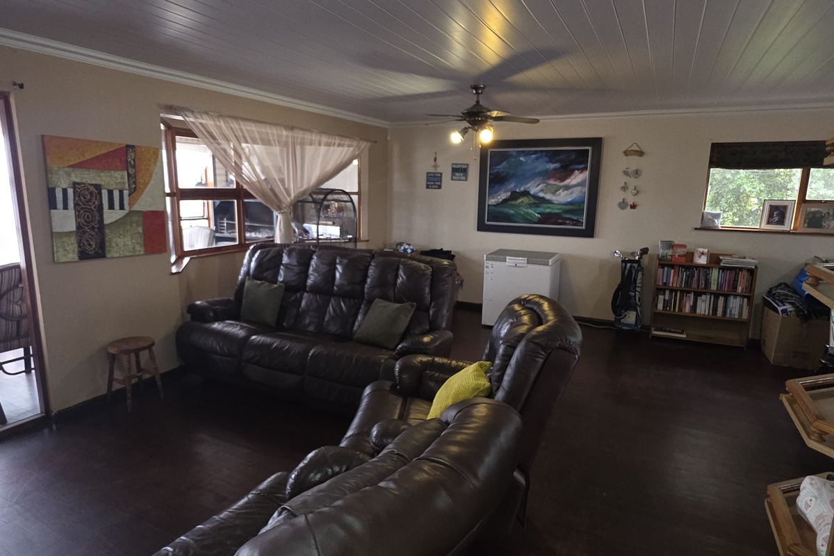 Spacious living room featuring dark timber-look flooring, a tongue and groove ceiling with a fan, and direct access to an adjoining patio area.