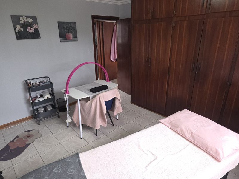 A bedroom featuring tiled flooring and extensive built-in wooden cabinetry, currently utilized as a treatment room.