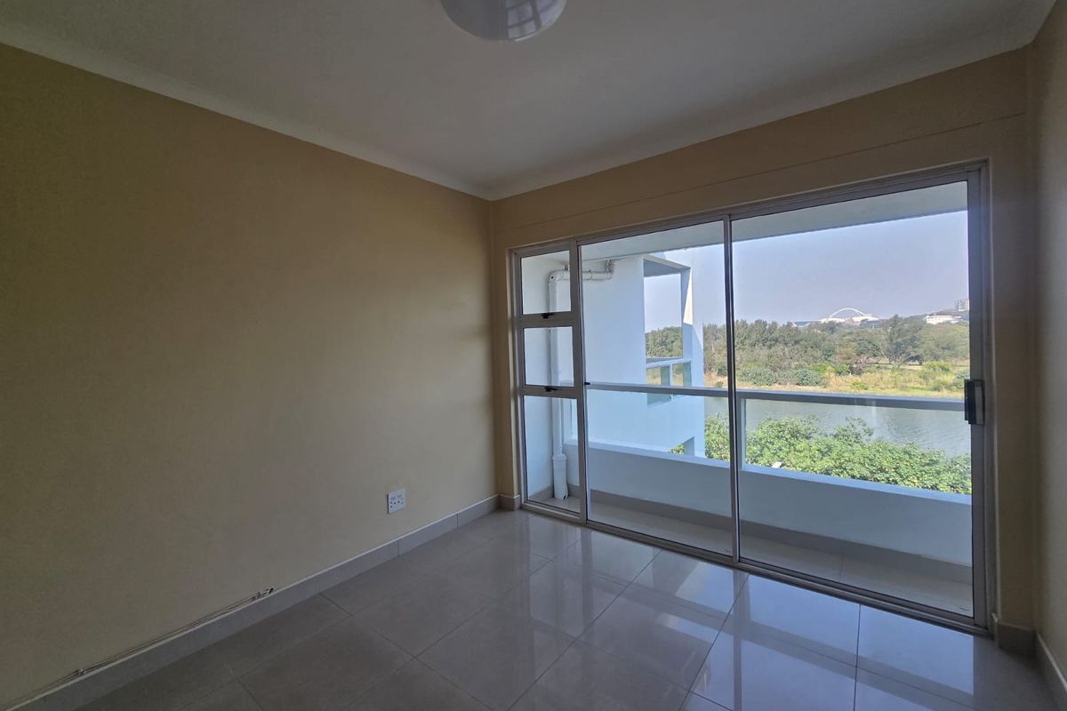An empty bedroom featuring tiled flooring and a large sliding glass door that opens onto a balcony with scenic views.