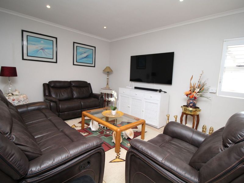 A well-maintained living room featuring recessed downlighting and a functional louvre window, providing a comfortable and bright space for relaxation.